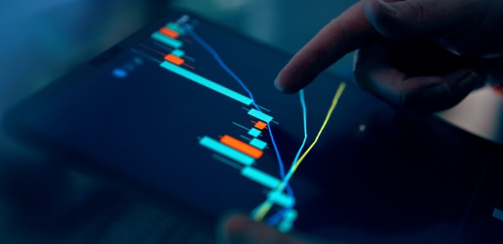 Close-up of a finger pointing at a financial trading chart on a tablet