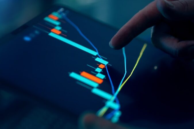 Close-up of a finger pointing at a financial trading chart on a tablet