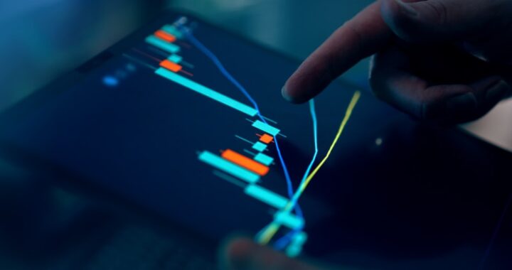 Close-up of a finger pointing at a financial trading chart on a tablet
