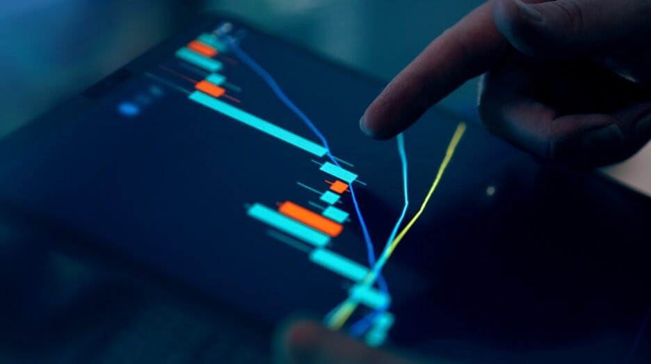 Close-up of a finger pointing at a financial trading chart on a tablet