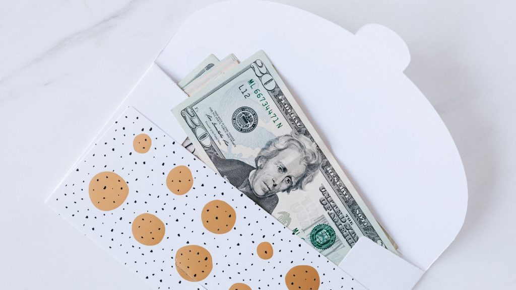 An envelope with decorative design containing dollar bills partially visible