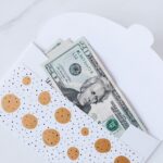 An envelope with decorative design containing dollar bills partially visible