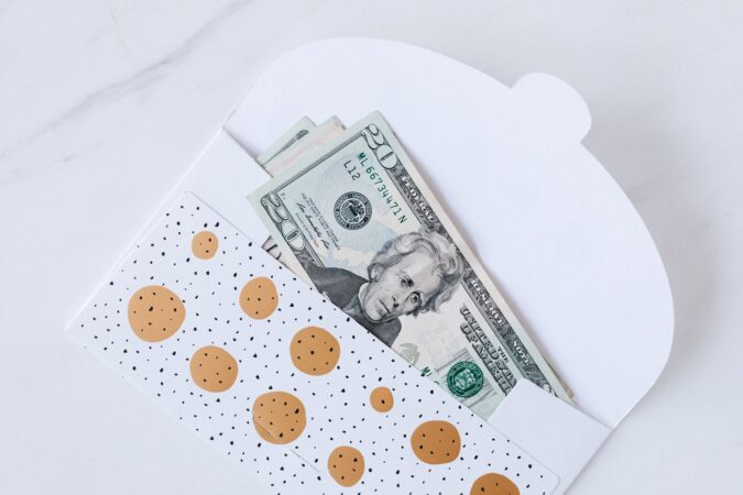 An envelope with decorative design containing dollar bills partially visible
