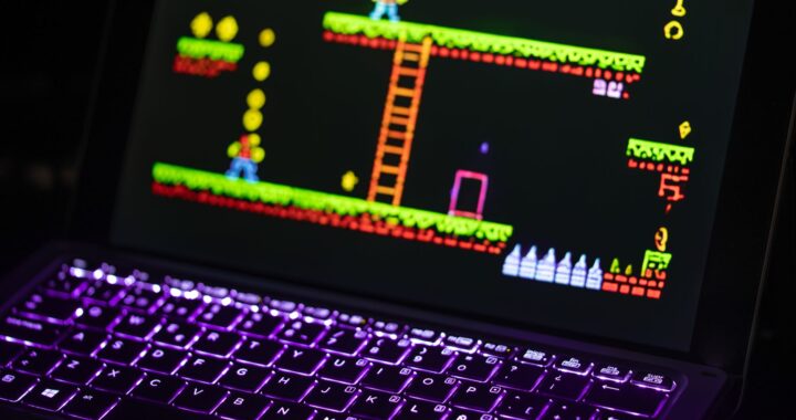 Close-up of a keyboard in front of a colorful retro video game screen